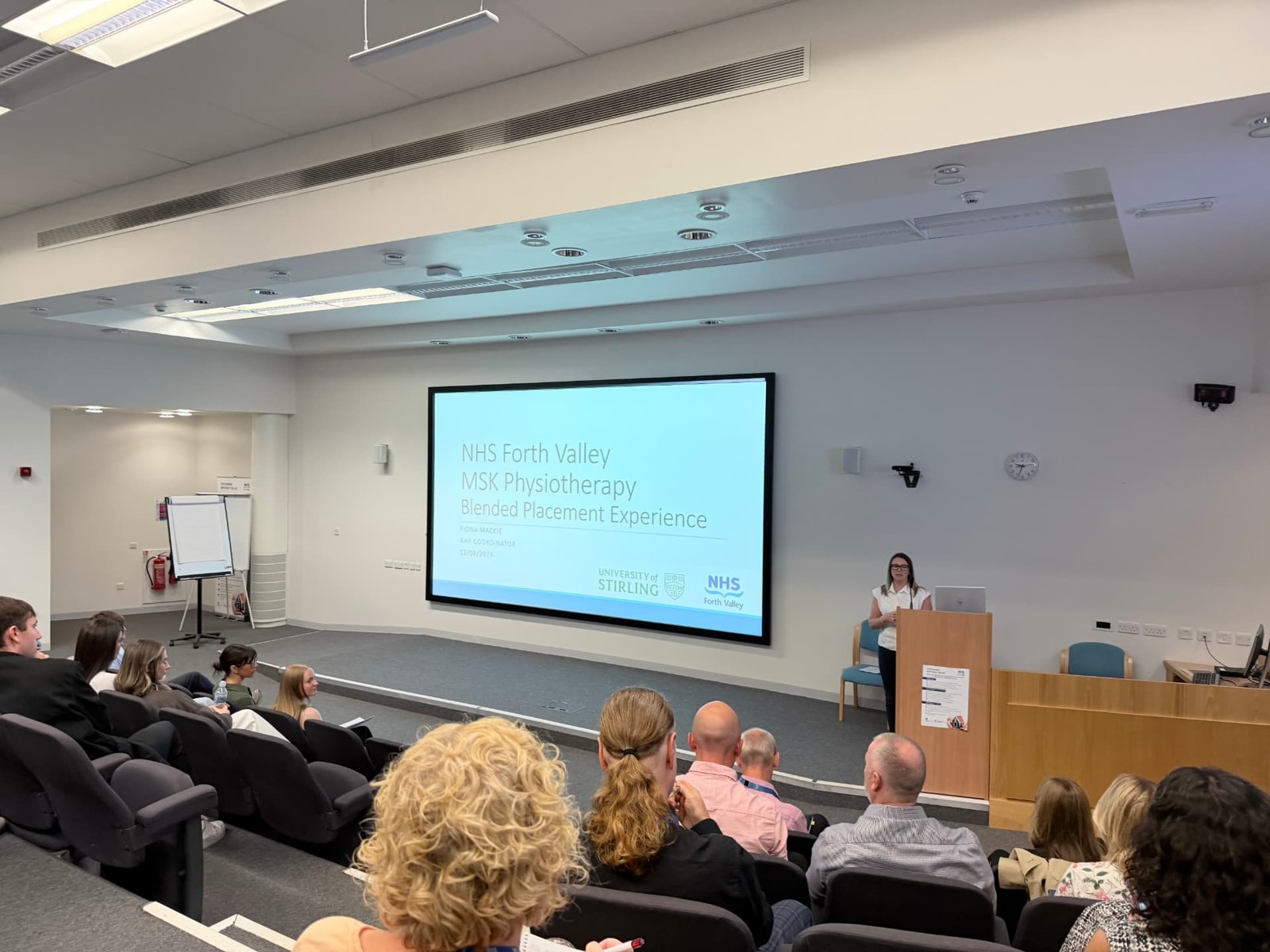 Audience in a lecture theatre watching a presentation titled NHS Forth Valley MSK Physiotherapy Blended Placement Experience